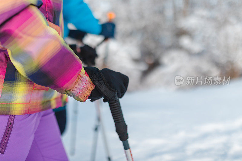 特写的徒步旅行者抱着一个徒步杆/工作人员，而徒步旅行在雪地里
